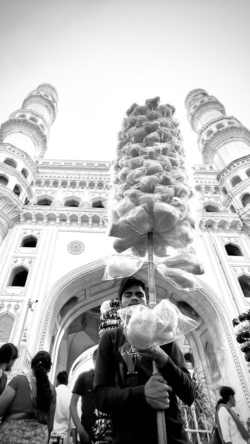 A man is holding a large flower in front of a large building