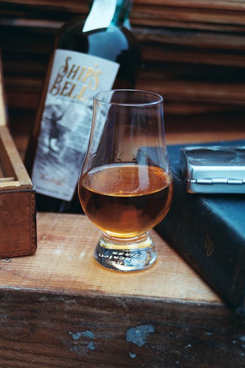 A glass of whiskey sitting on top of a wooden table