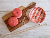 木板上美观的扁平布局由毛线球、织针和图案碗组成