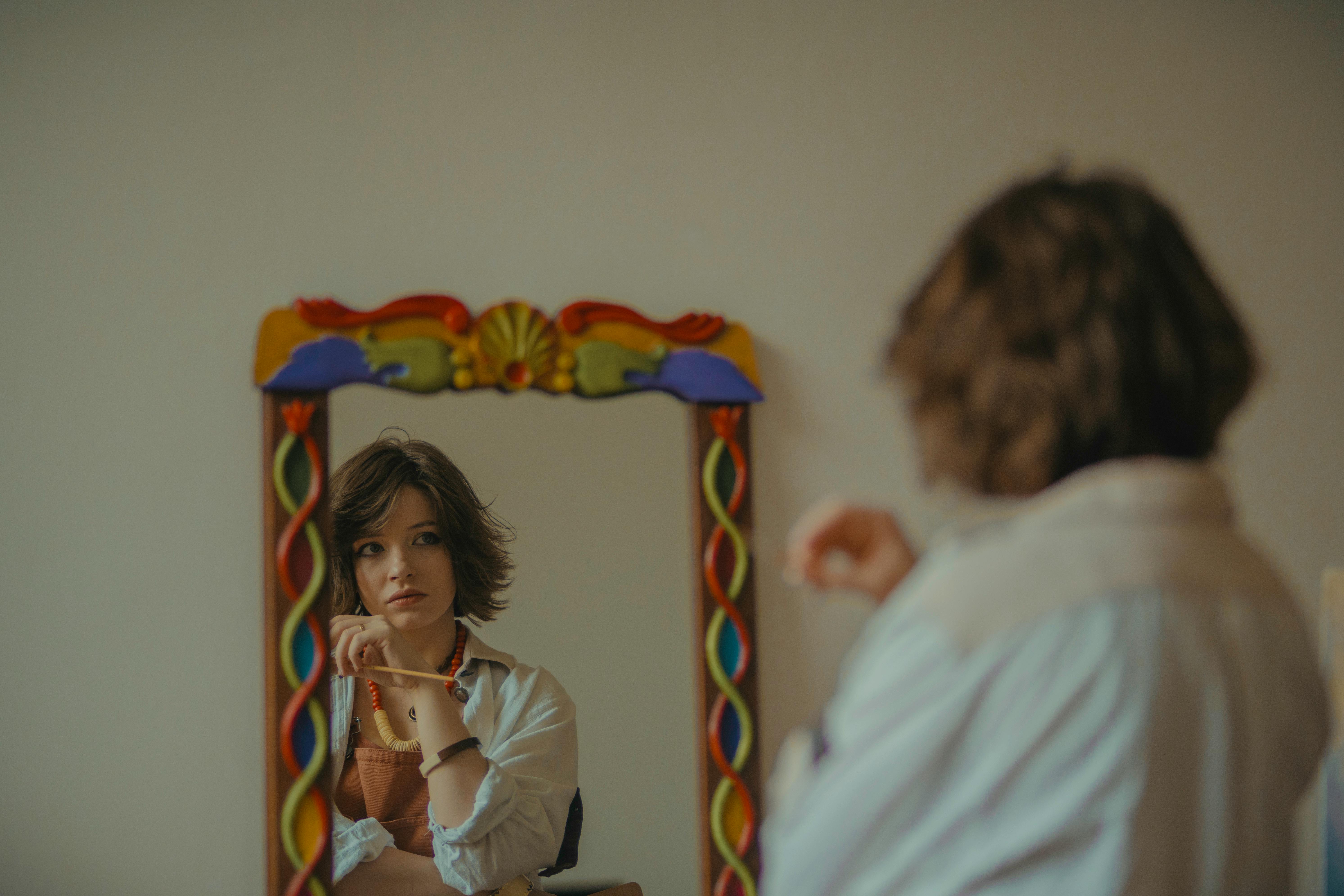 A woman is looking in the mirror