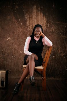 Fashionable woman in black dress posing elegantly, showcasing style and grace in a studio setting.