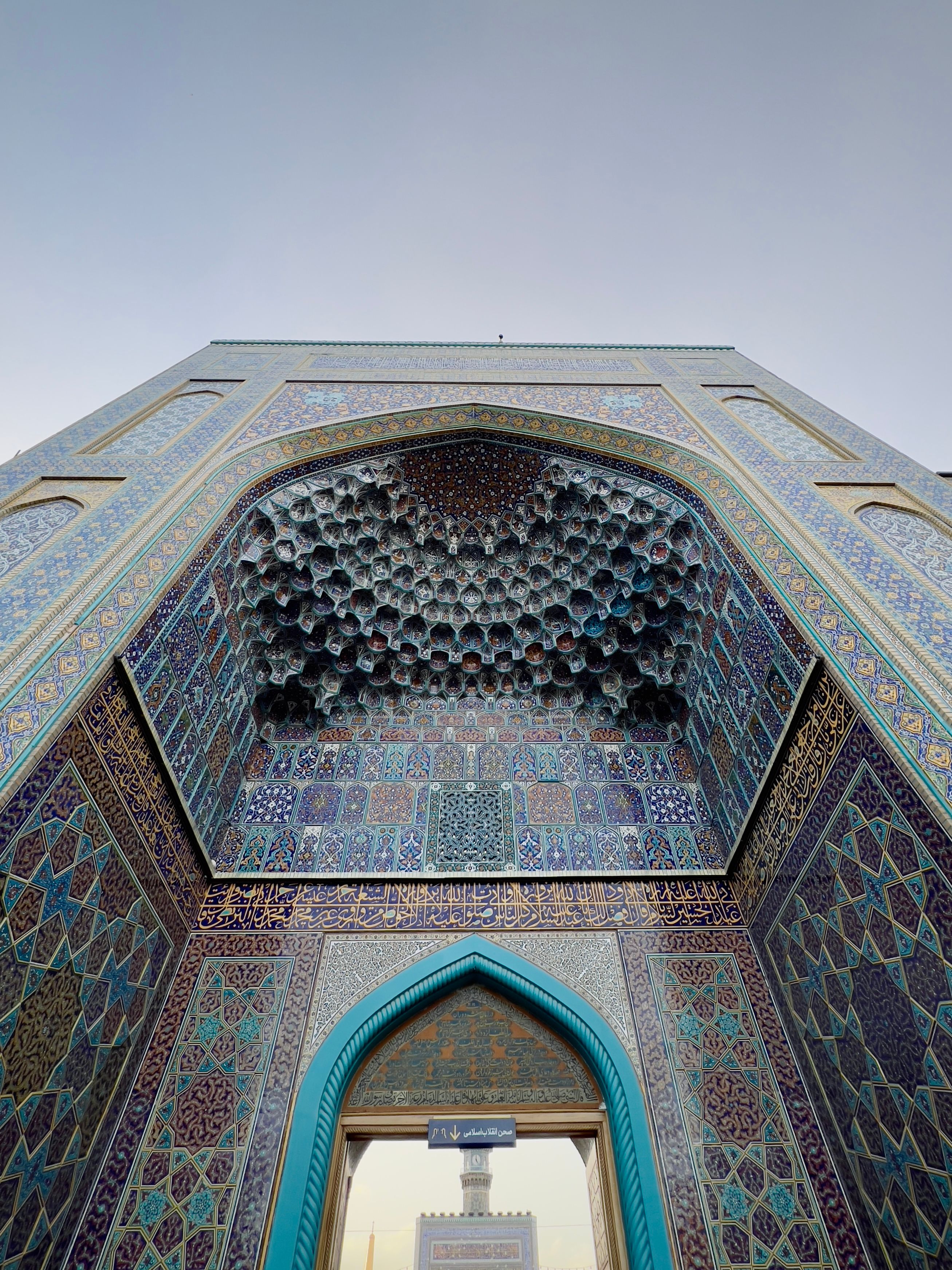 Low-angle view of intricate tilework at Imam Reza Shrine in Mashhad, Iran, showcasing Islamic art.