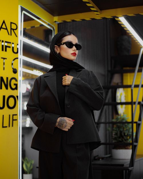 Free Fashionable woman in black outfit posing indoors with sunglasses and red lips in a modern setting. Stock Photo