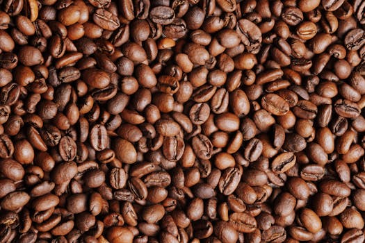 Close-up view of fresh brown coffee beans in a heap, showcasing their texture and abundance.