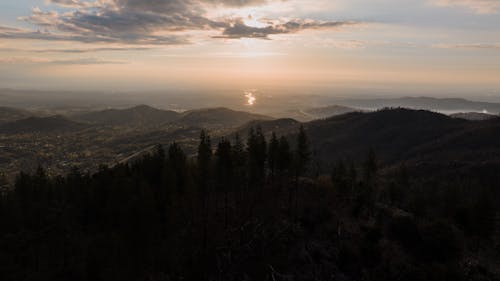 A sunset over a mountain range with trees and water