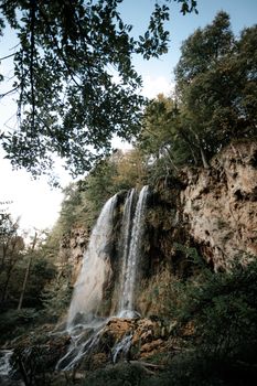 A stunning vertical view of a waterfall cascading through a lush forest, showcasing nature's beauty and tranquility.