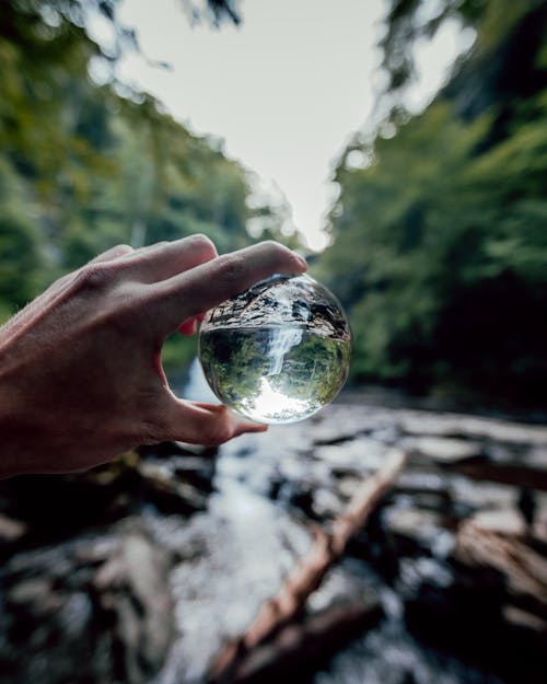 A person holding a crystal ball in front of a river