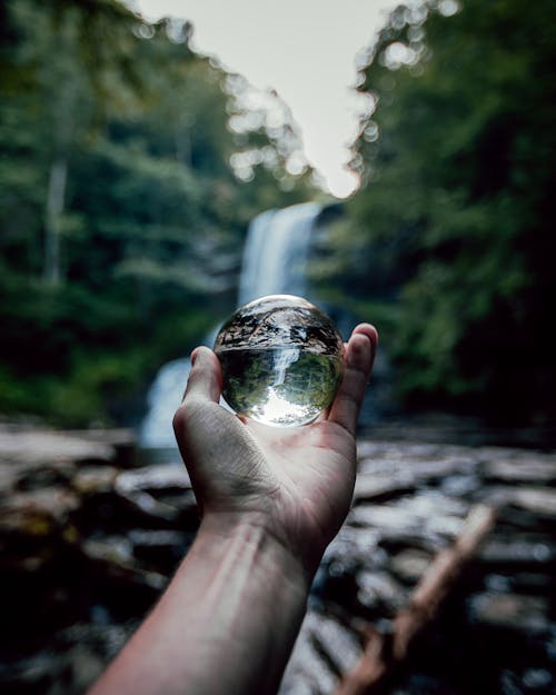 A person holding a crystal ball in front of a waterfall