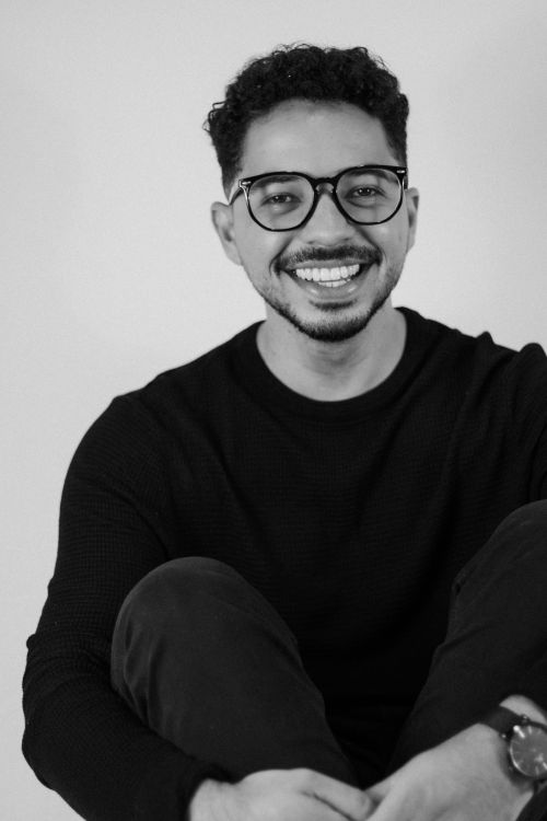 Free Black and white portrait of a young man wearing glasses, smiling warmly. Stock Photo