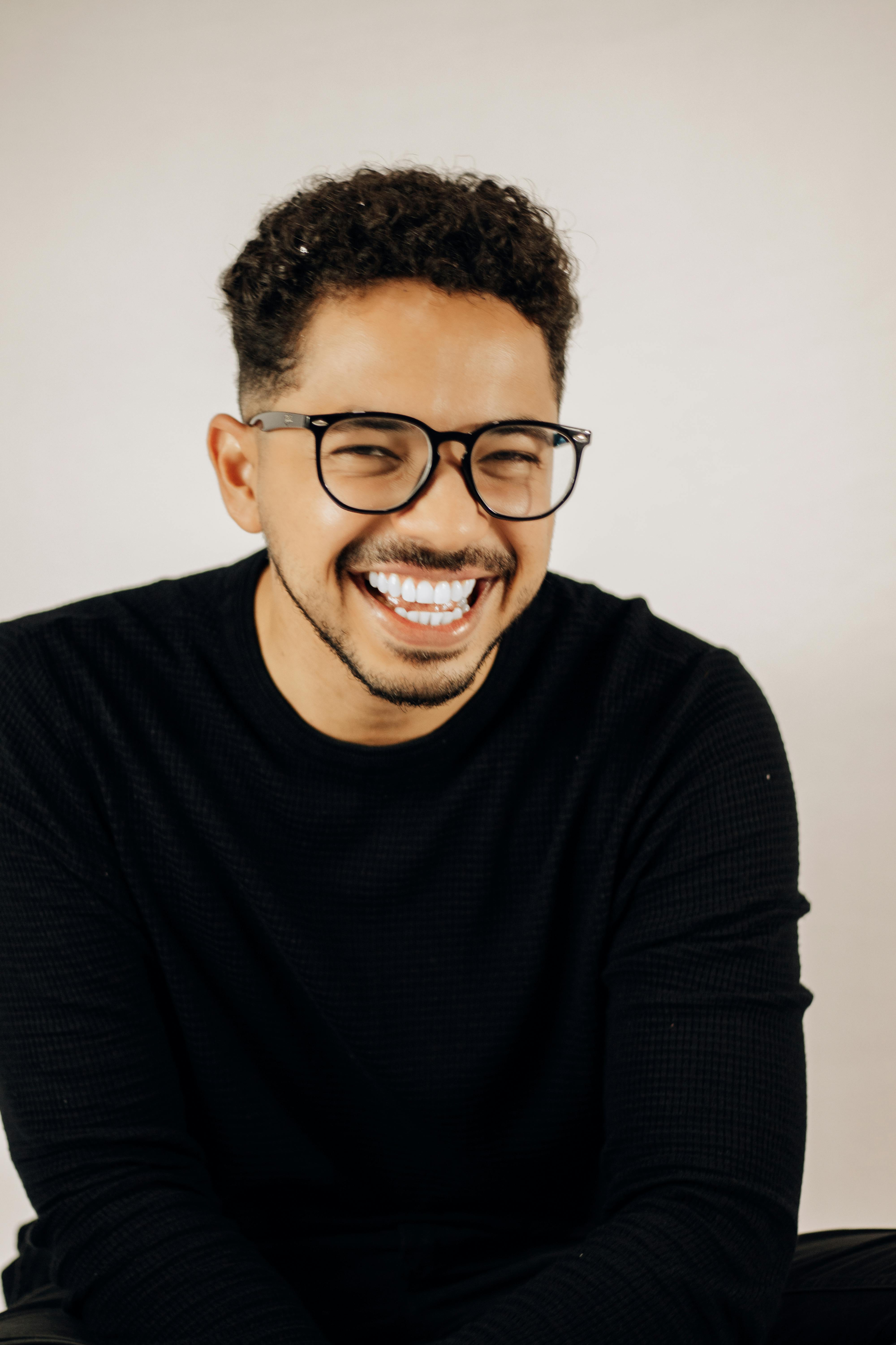 Cheerful man with eyeglasses, beard, and mustache laughing in a studio setting.
