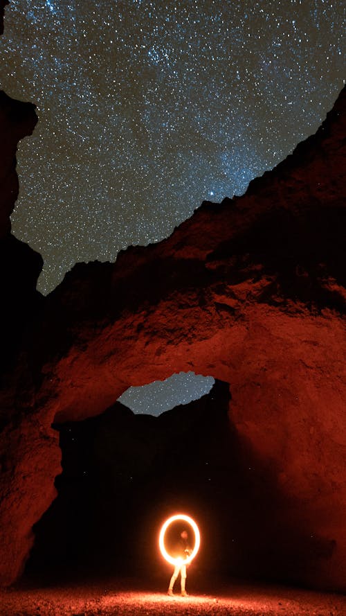 Man Holding Rounded Light in a Canyon at Night 