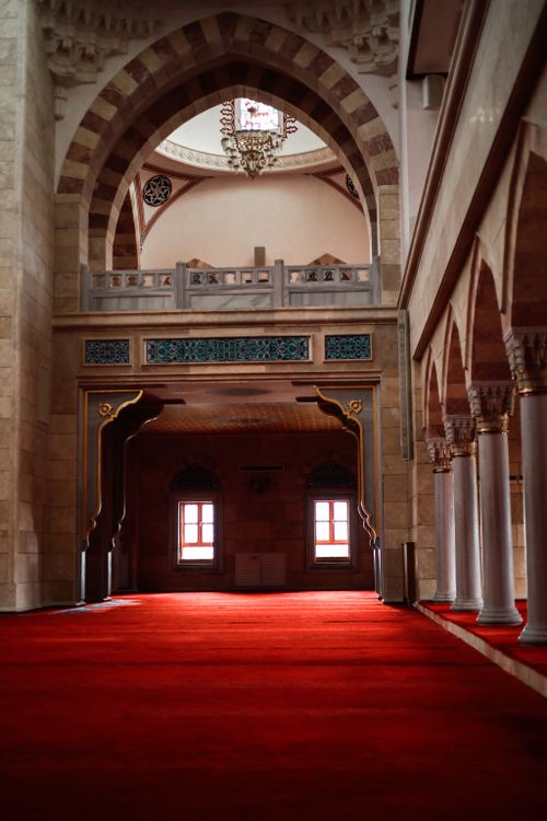 Free A stunning mosque interior featuring decorative arches and plush red carpet. Stock Photo
