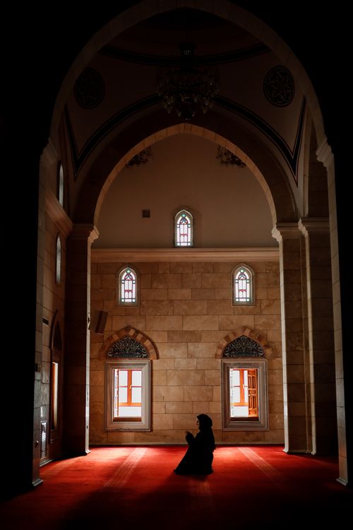 Free Silhouette of a woman praying inside a mosque, highlighting Islamic architecture. Stock Photo