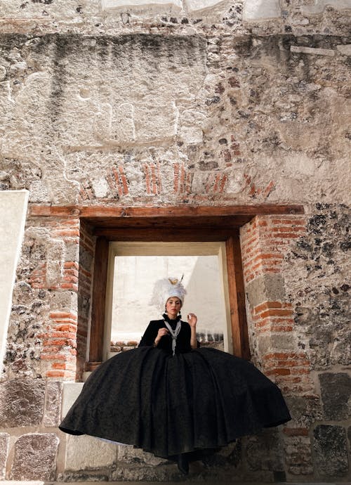 A woman in a black dress sitting on a window ledge