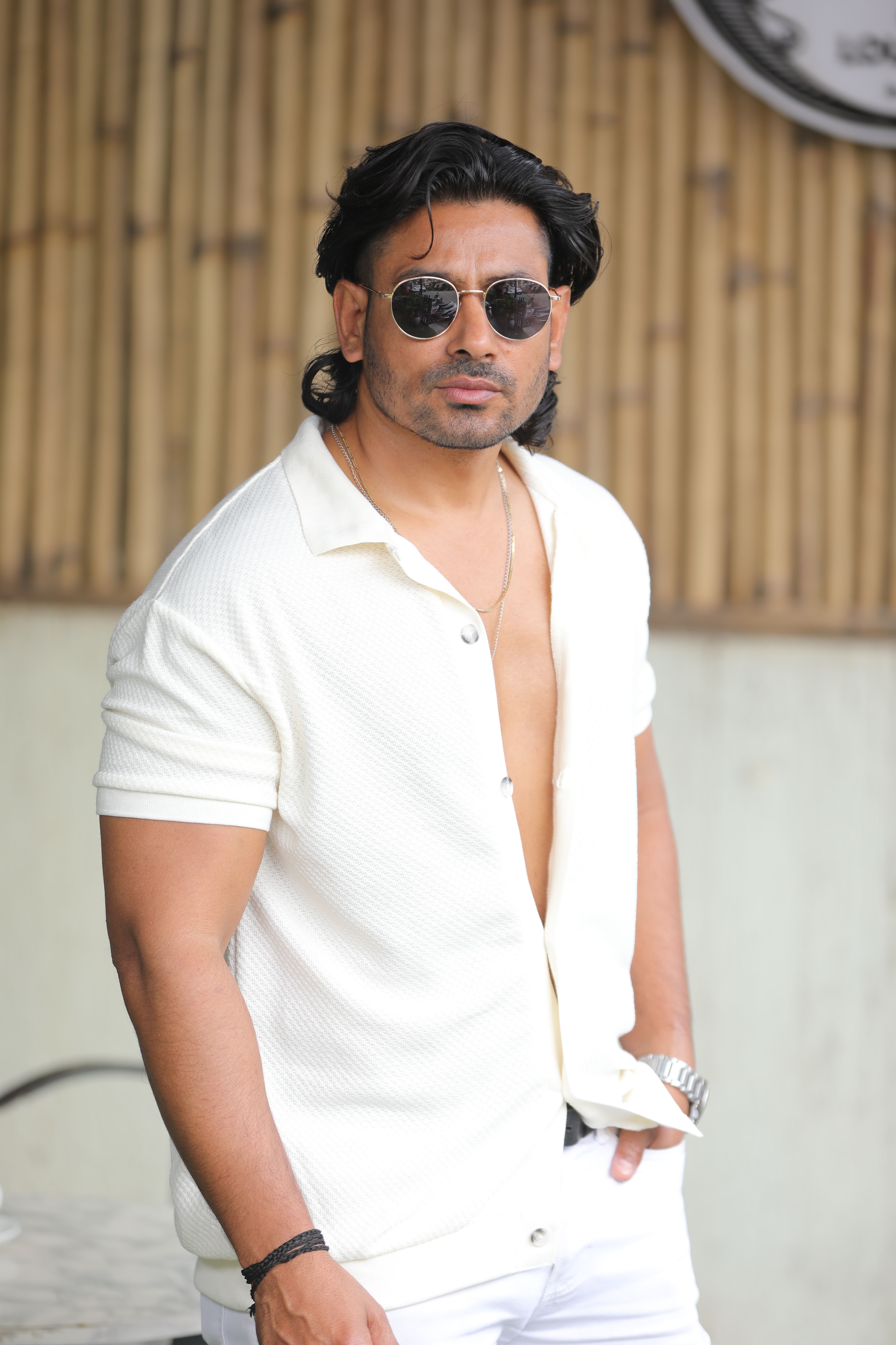 Confident man wearing sunglasses and casual summer attire, standing outdoors.