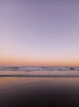 Calm sea waves at dawn with a pastel-colored sky, offering tranquility and beauty.