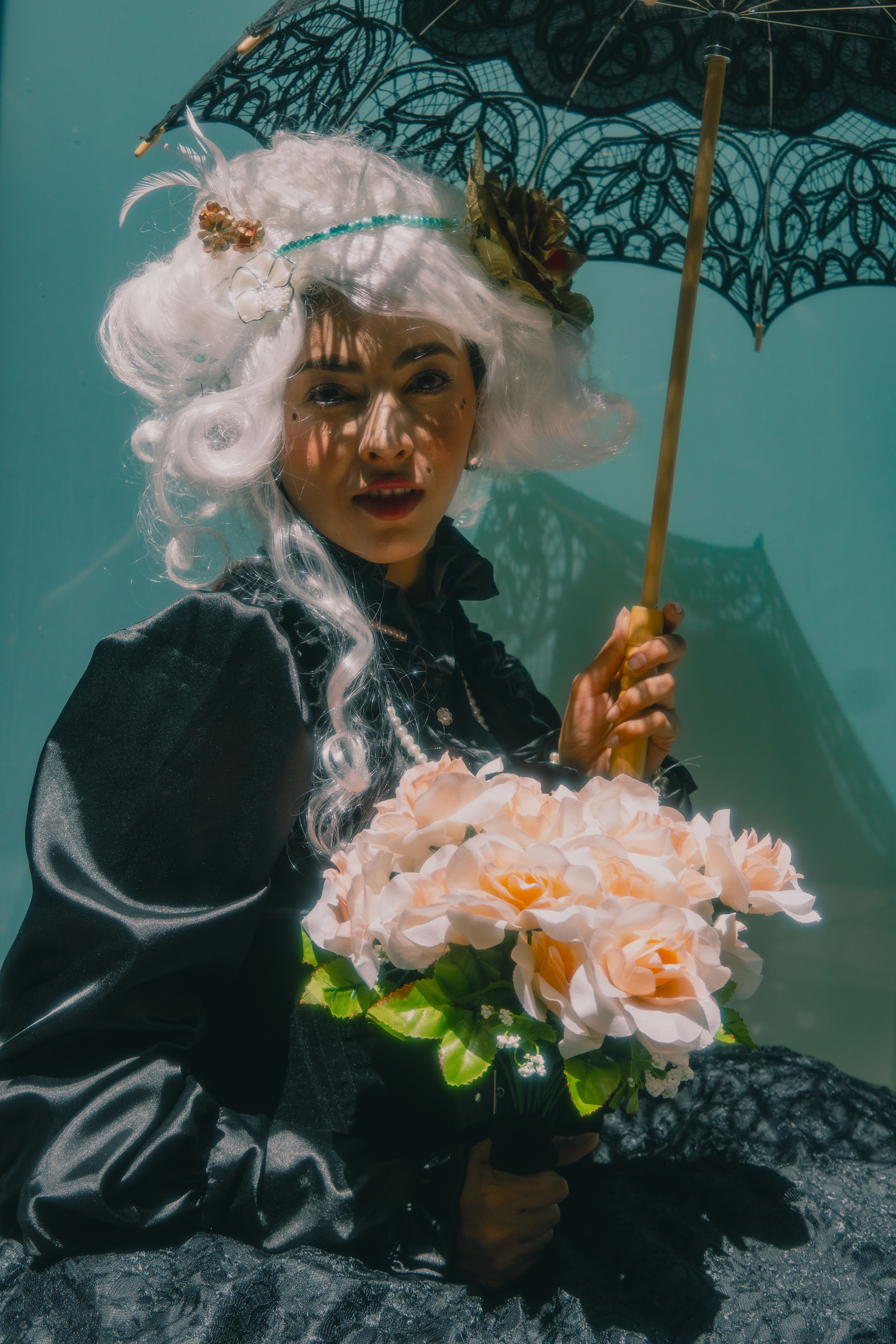 Woman in an elegant vintage costume holding a bouquet under a lace umbrella, Mexico City.