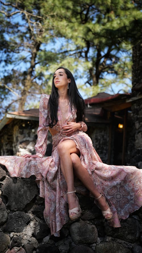 A woman in a long dress sitting on a rock