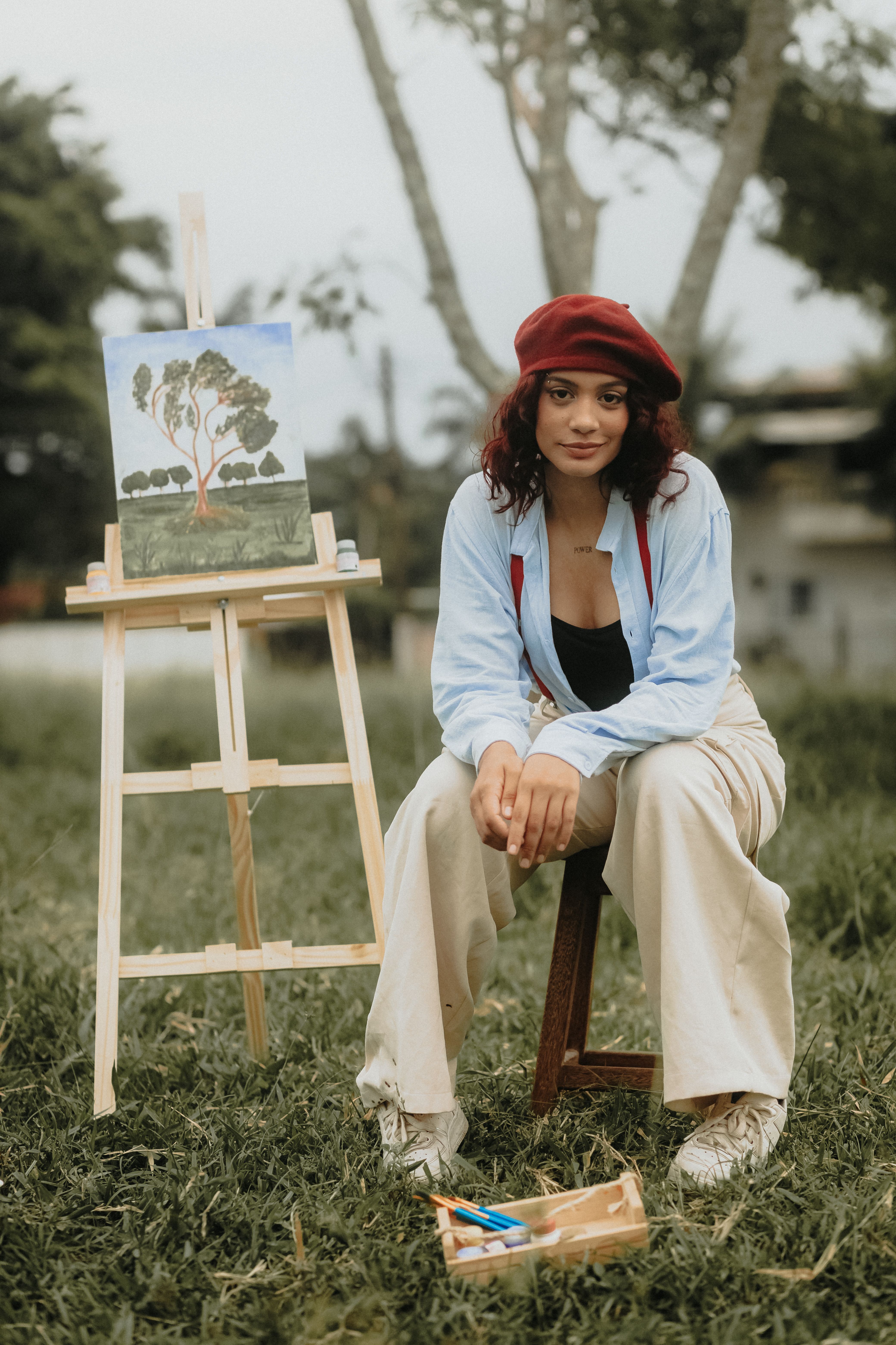 Woman in Beret and Shirt Sitting with Painting on Grass · Free Stock Photo