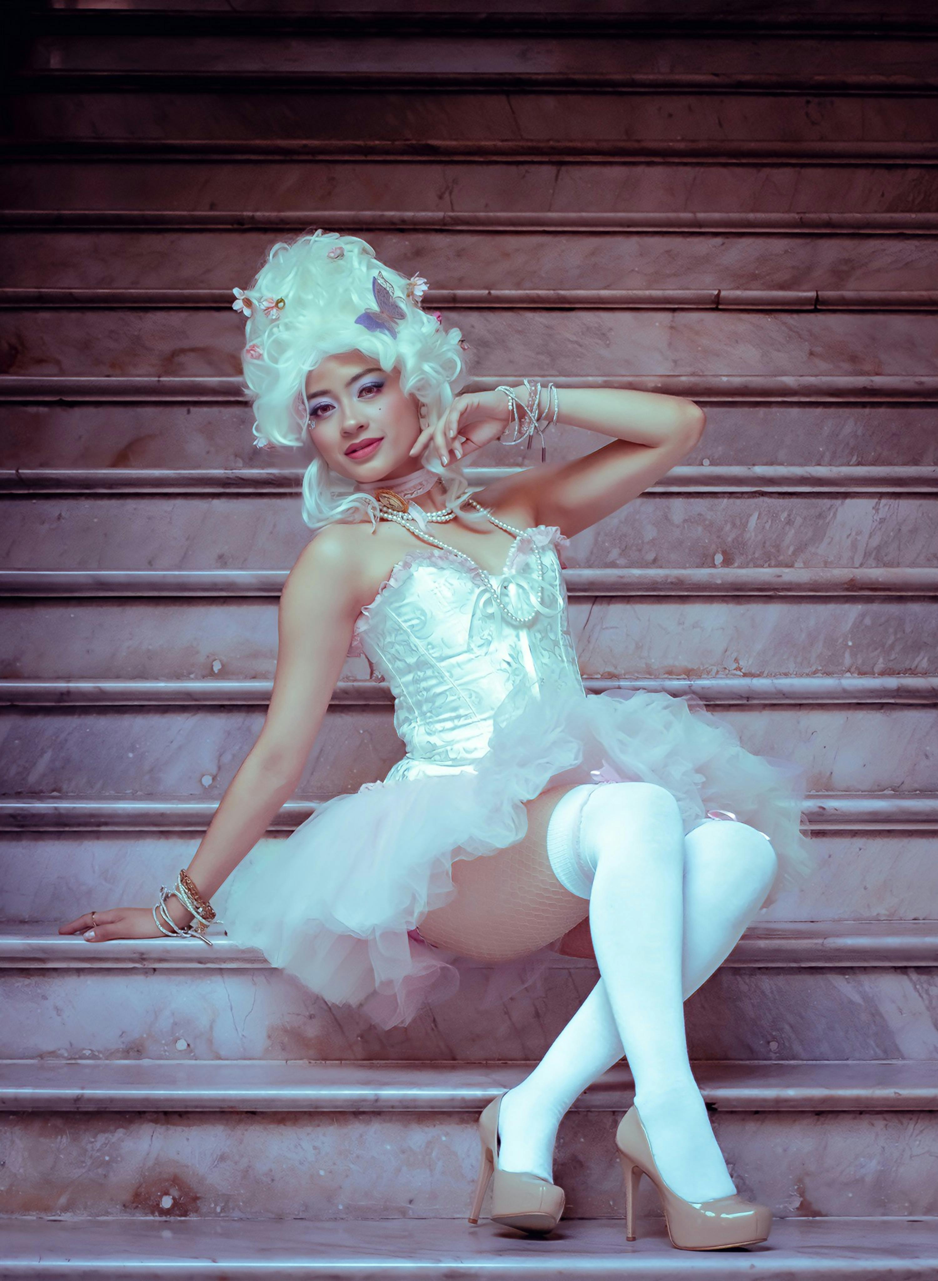 A model poses in a Marie Antoinette-inspired costume on stairs, exuding elegance and historical charm.