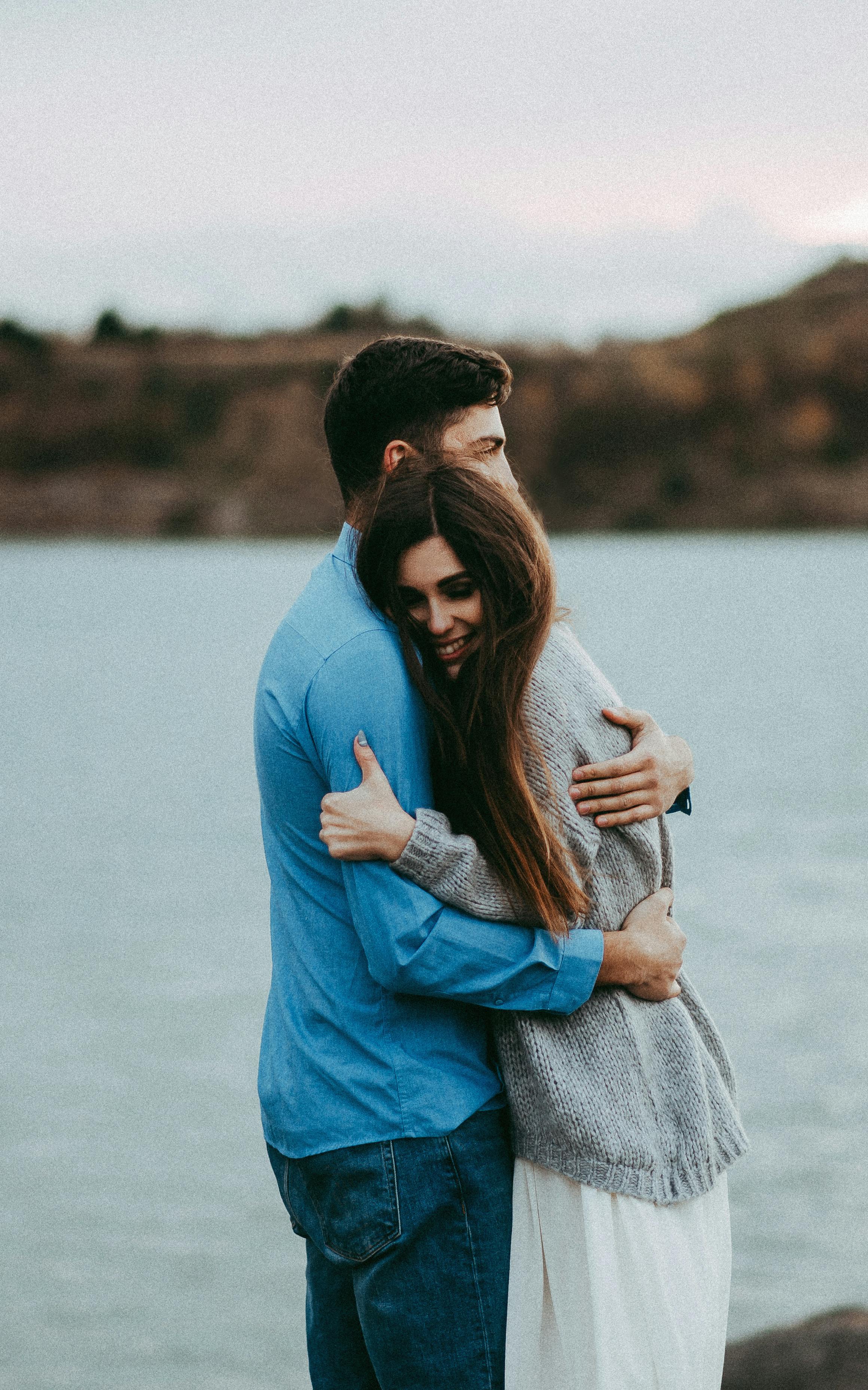 Man hugging a woman near a body of water. | Photo: Pexels