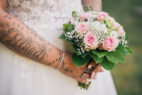 A bride with tattoos holding a bouquet