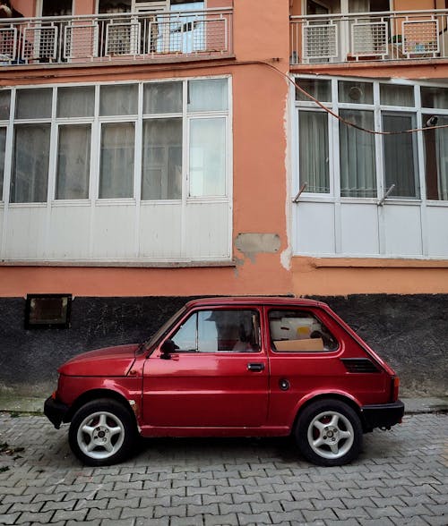 A small red car parked in front of a building