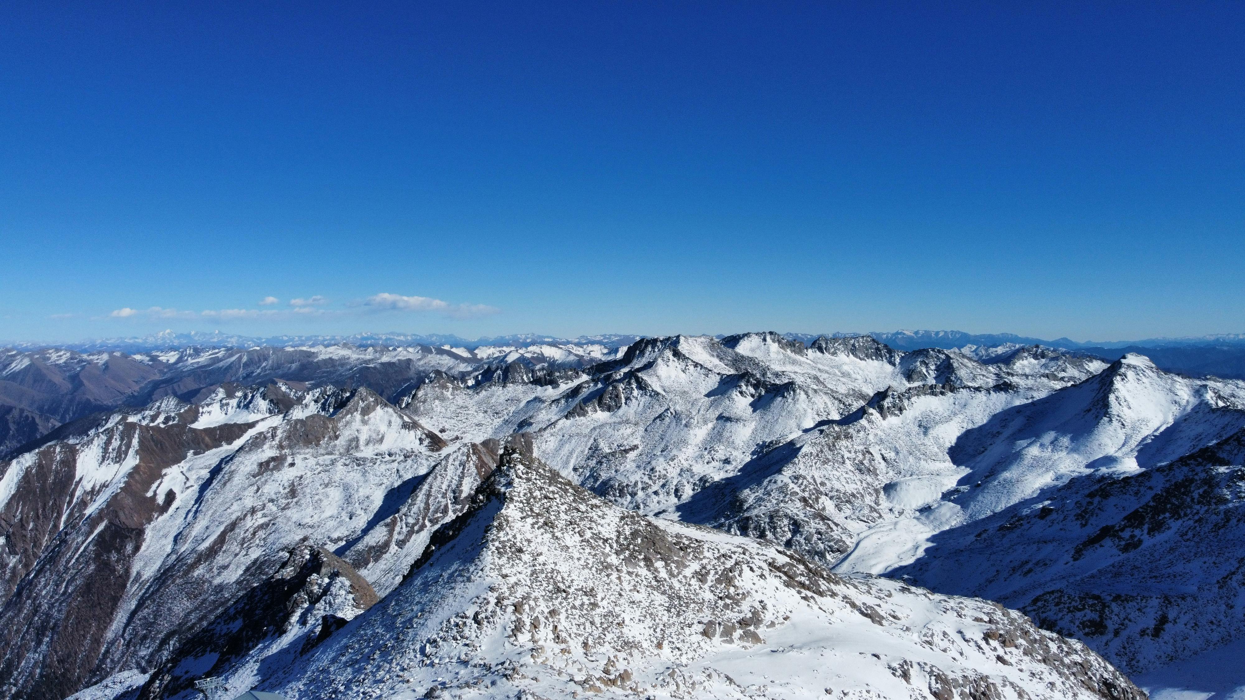 A breathtaking aerial view of snow-covered mountain peaks under a clear blue sky.