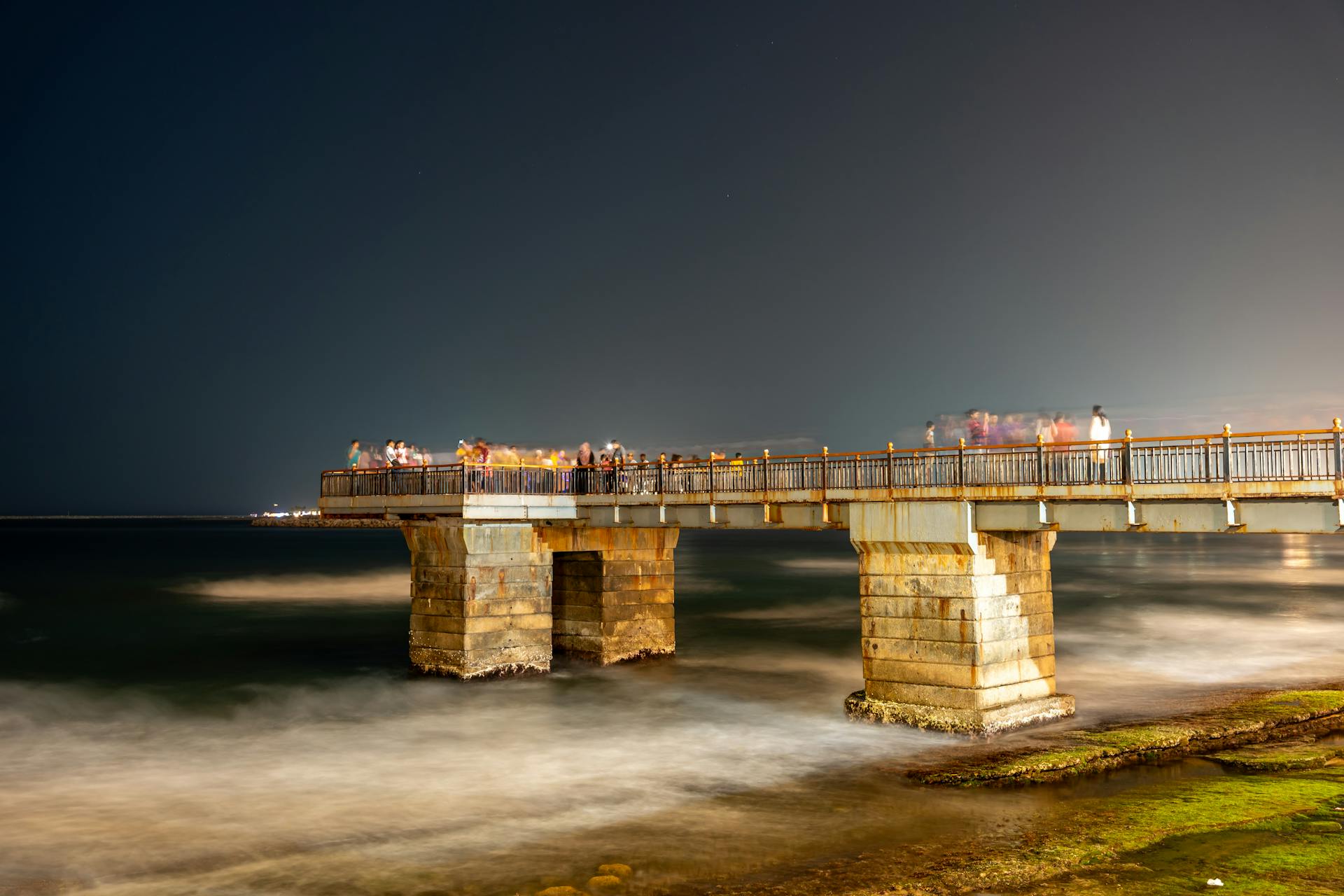 Stunning night view of the Galle Face pier in Colombo with tourists enjoying the sea breeze.