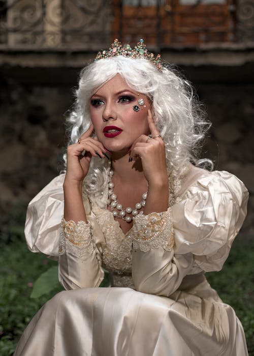 A woman in white with a crown and pearls