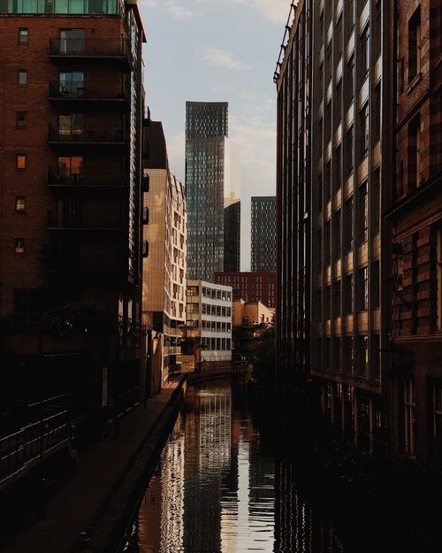 Free Dramatic urban canal framed by buildings with cityscape reflections at twilight. Stock Photo