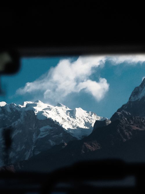 Free Stunning view of snow-covered mountains with clouds against a bright blue sky. Stock Photo