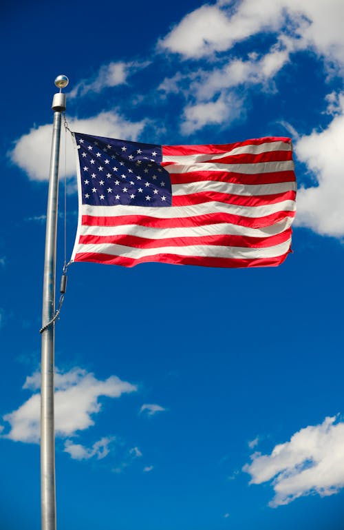 An american flag flying in the wind against a blue sky
