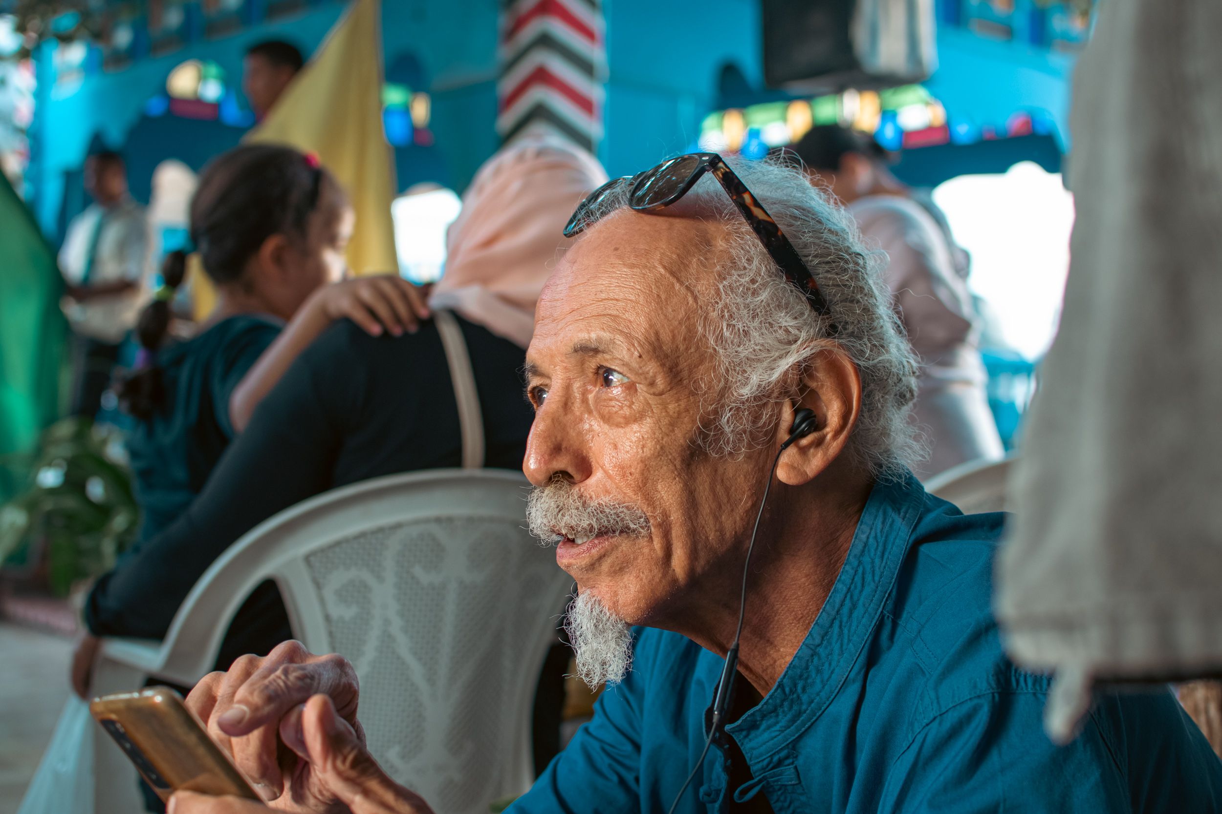 Portrait of an elderly man with earphones in a vibrant café in La Marsa, Tunisia.