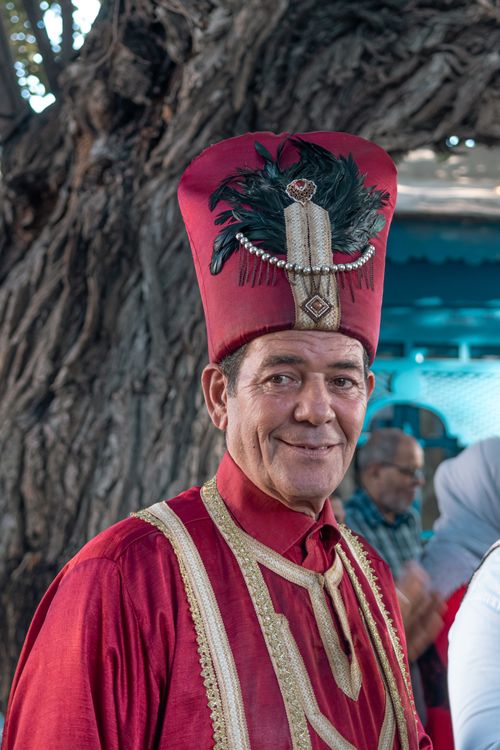 Free Smiling man in ornate red traditional clothing and fez with decorative feathers in La Marsa, Tunisia. Stock Photo