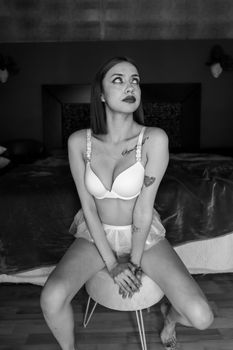 Black and white portrait of a woman sitting in lingerie, showcasing elegance and style.