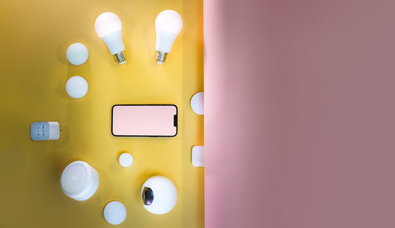 Smart home sensors, bulbs, and a phone on a table
