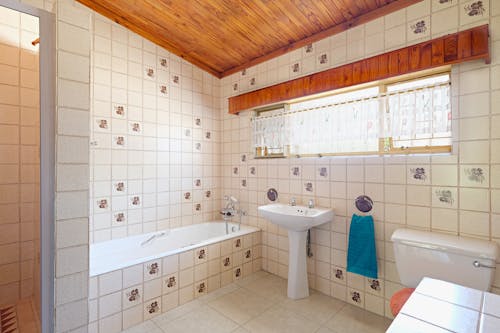 A bathroom with tile walls and a tub and toilet