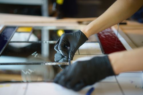Free Detailed image of stained glass crafting with hands in rubber gloves assembling pieces. Stock Photo