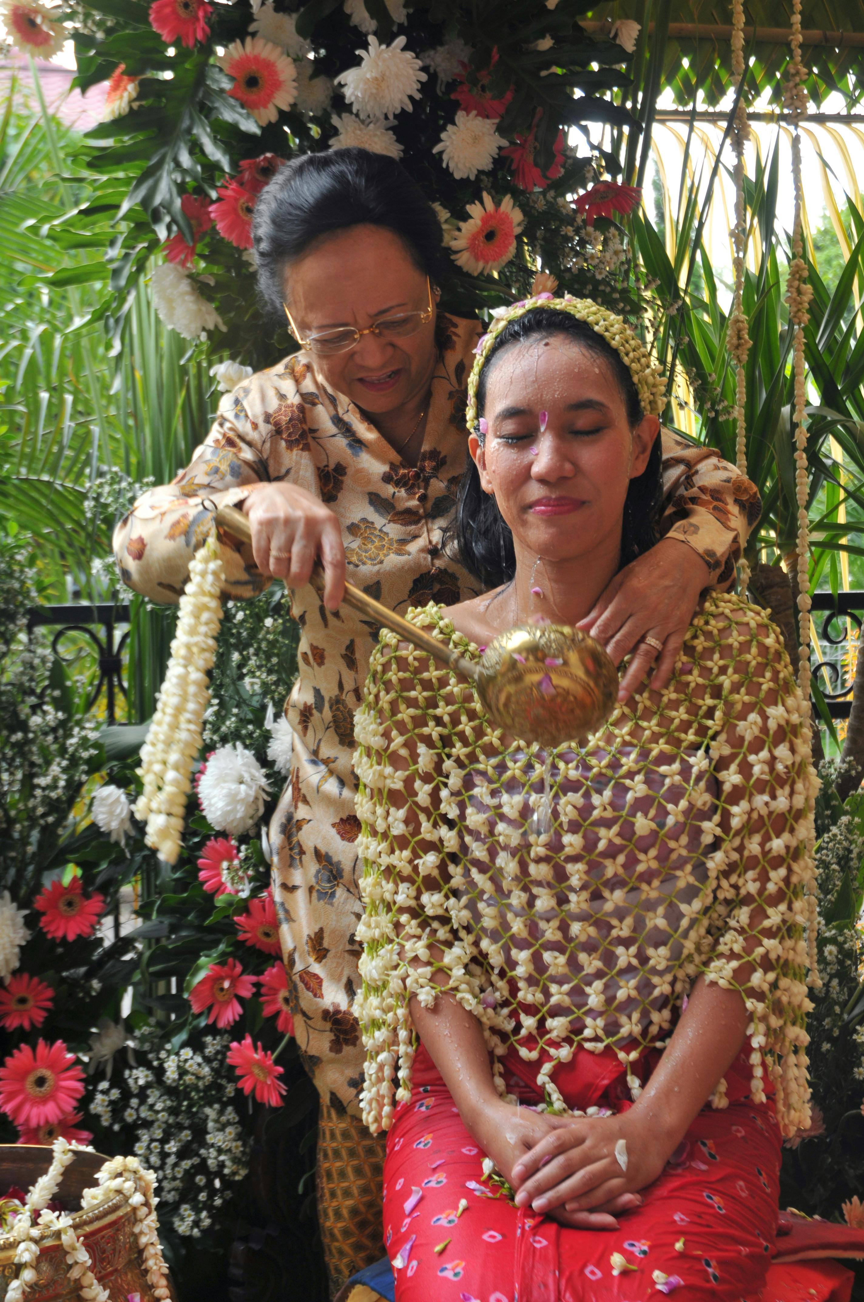 A woman participates in a traditional Indonesian siraman ceremony in Jakarta.
