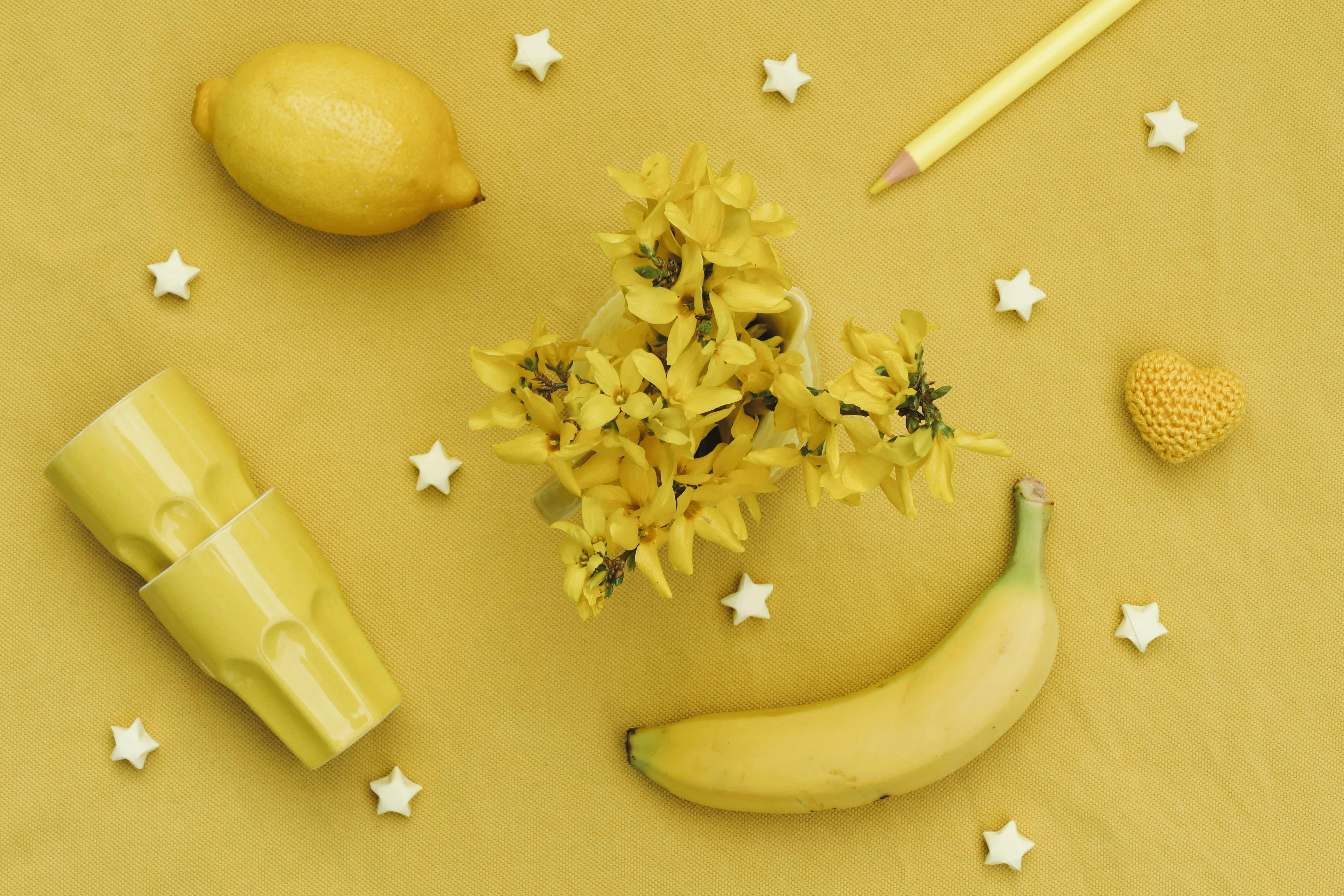 A vivid flat lay of yellow items including lemons, bananas, and forsythia flowers, creating a sunny still life.