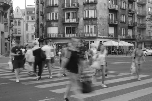 Blurred pedestrians crossing a street in Budapest captured in monochrome.