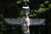 Stunning totem pole amidst lush forest in Vancouver, showcasing indigenous art.