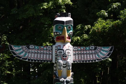 Stunning totem pole amidst lush forest in Vancouver, showcasing indigenous art.