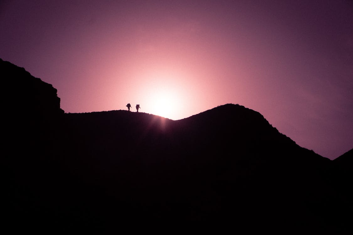 Free Silhouette Photo of Two Persons Standing on Black Mountain Peak Stock Photo