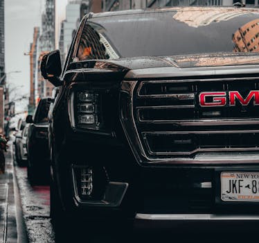 Black GMC vehicle parked on rainy New York City streets, showcasing urban lifestyle.