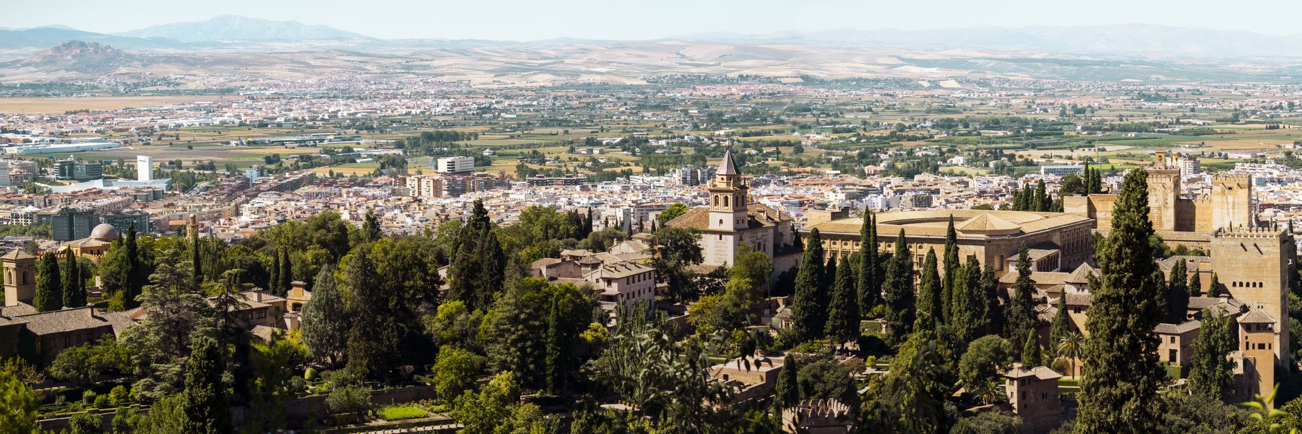 Panoramic view of Alhambra and Granada, Spain with distant hills and bustling city life.