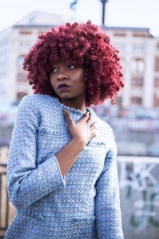 Elegant woman with striking curly hairstyle posing outdoors in fashionable attire.
