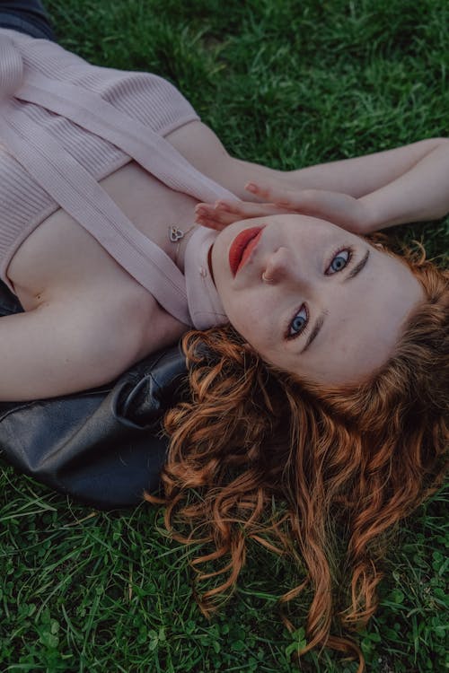 Free A woman laying on the grass with red hair Stock Photo