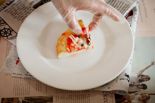 A person holding a piece of pizza on a plate